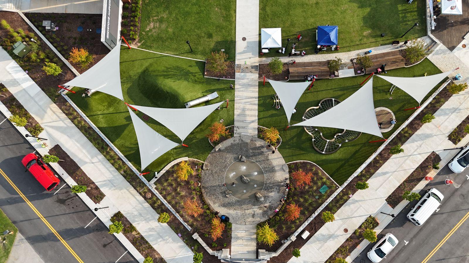 Shade sail canopies over a splash pad and play area
