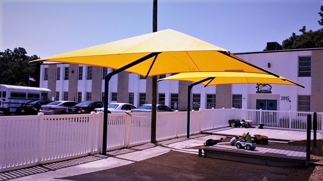 Cantilever umbrella shade structures over a playground